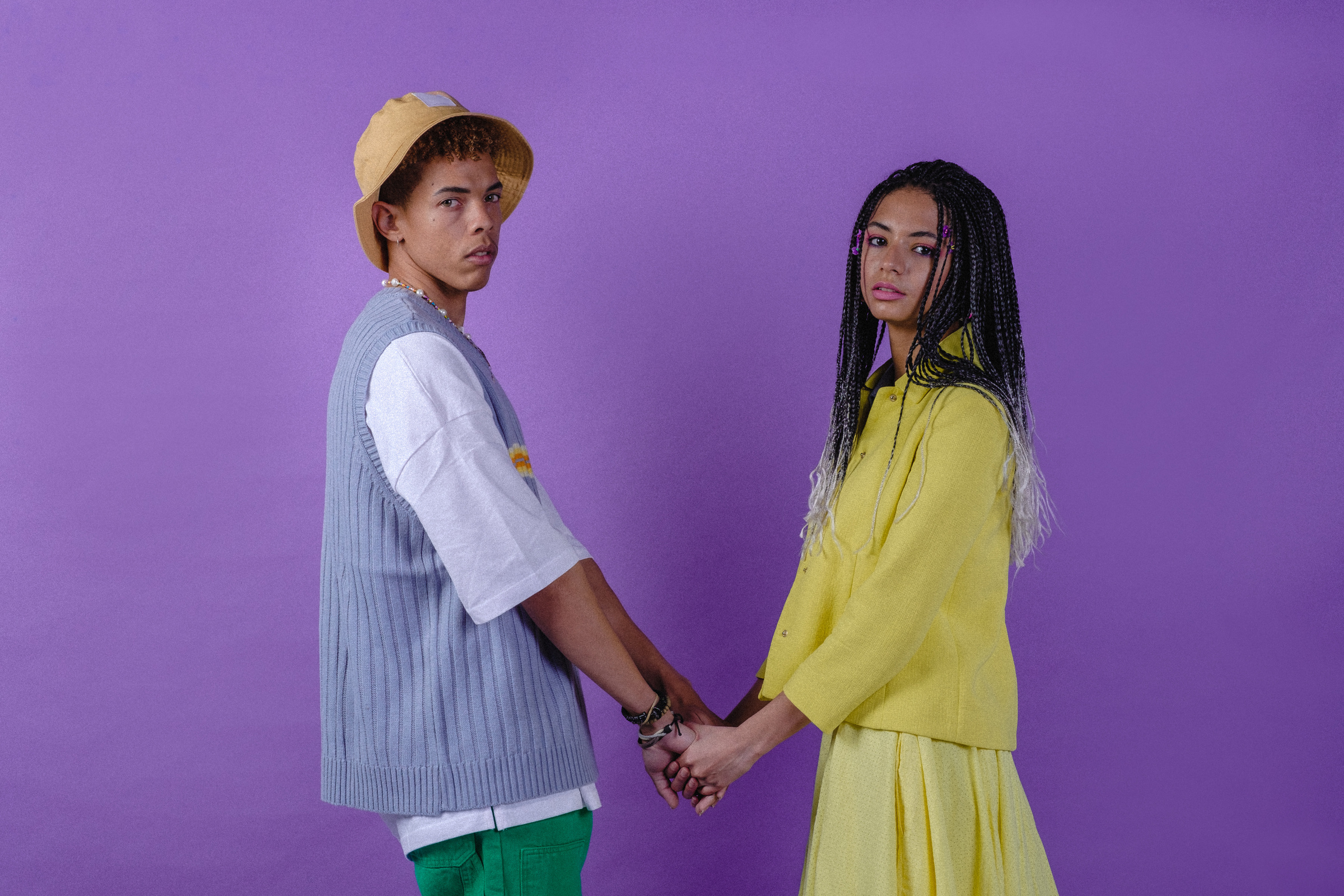 Stylish Couple Holding Hands on Purple Background
